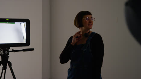 Female-Film-Production-Assistant-With-Headset-Standing-By-Monitor-On-Movie-Or-Video-Shoot-In-Studio